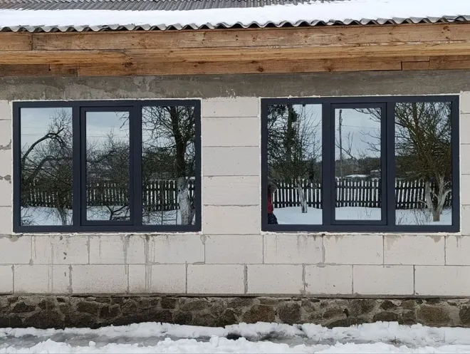 Стрічка темних металопластикових вікон у будинку з газоблоку